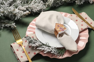 Photo of Christmas place setting and festive decor on green table, closeup