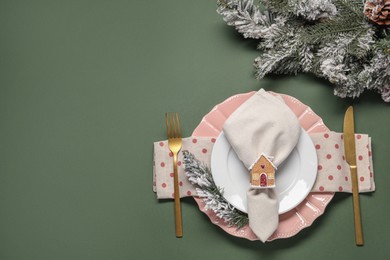 Photo of Christmas place setting and festive decor on green table, flat lay. Space for text