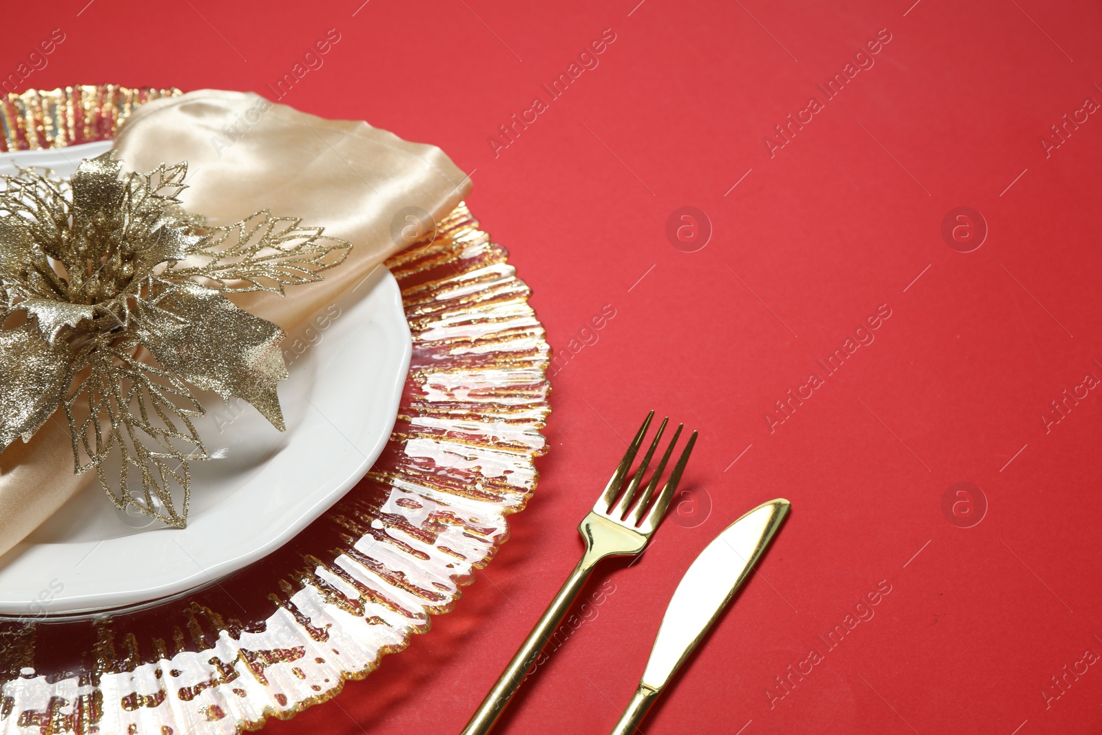 Photo of Christmas place setting and festive decor on red table, closeup. Space for text