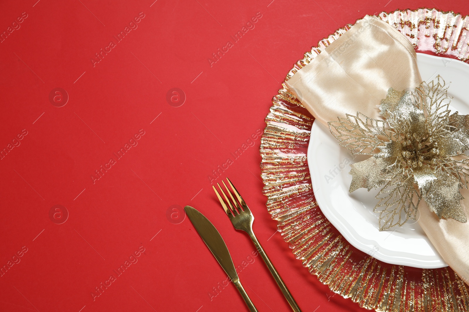 Photo of Christmas place setting and festive decor on red table, top view. Space for text