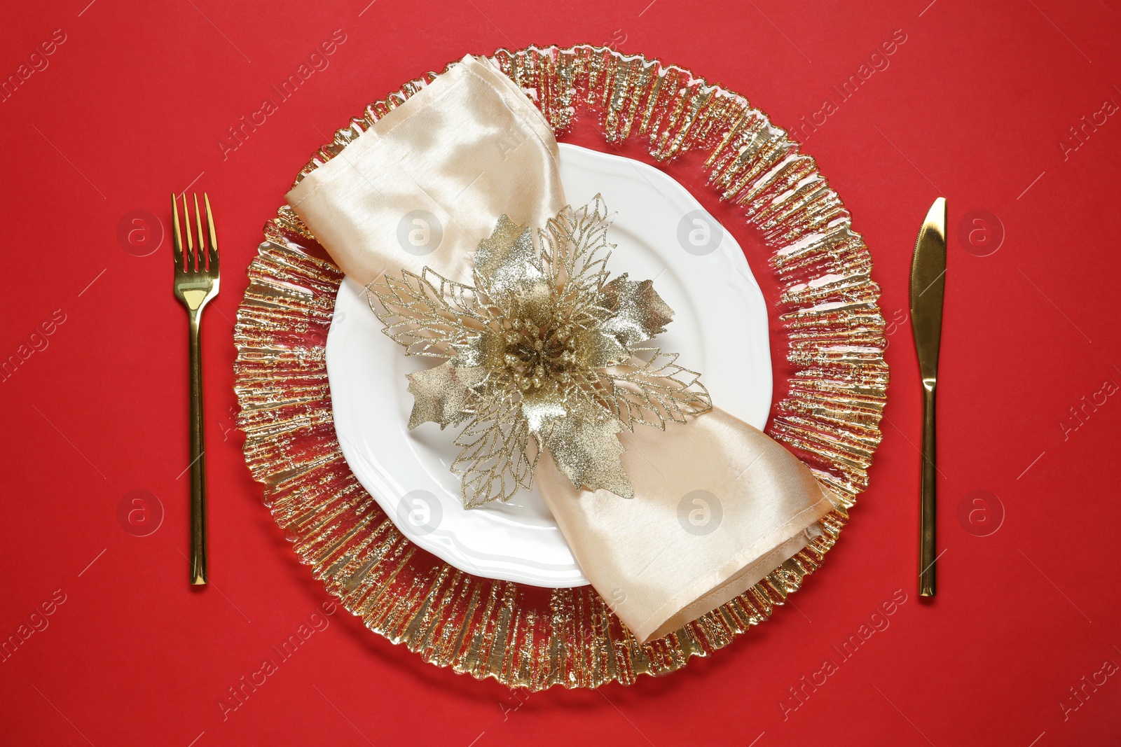 Photo of Christmas place setting and festive decor on red table, top view