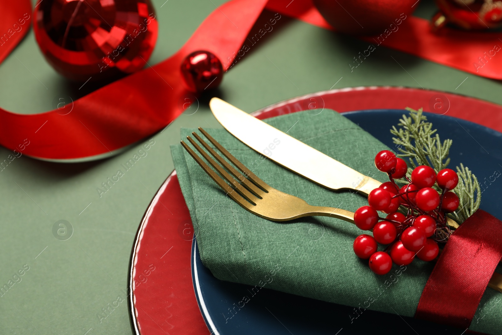 Photo of Christmas place setting and festive decor on green table, closeup