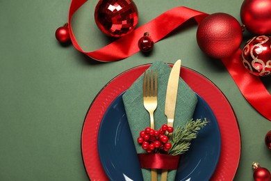 Photo of Christmas place setting with festive decor on green table, flat lay. Space for text