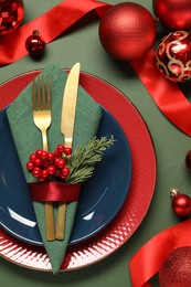 Photo of Christmas place setting and festive decor on green table, flat lay