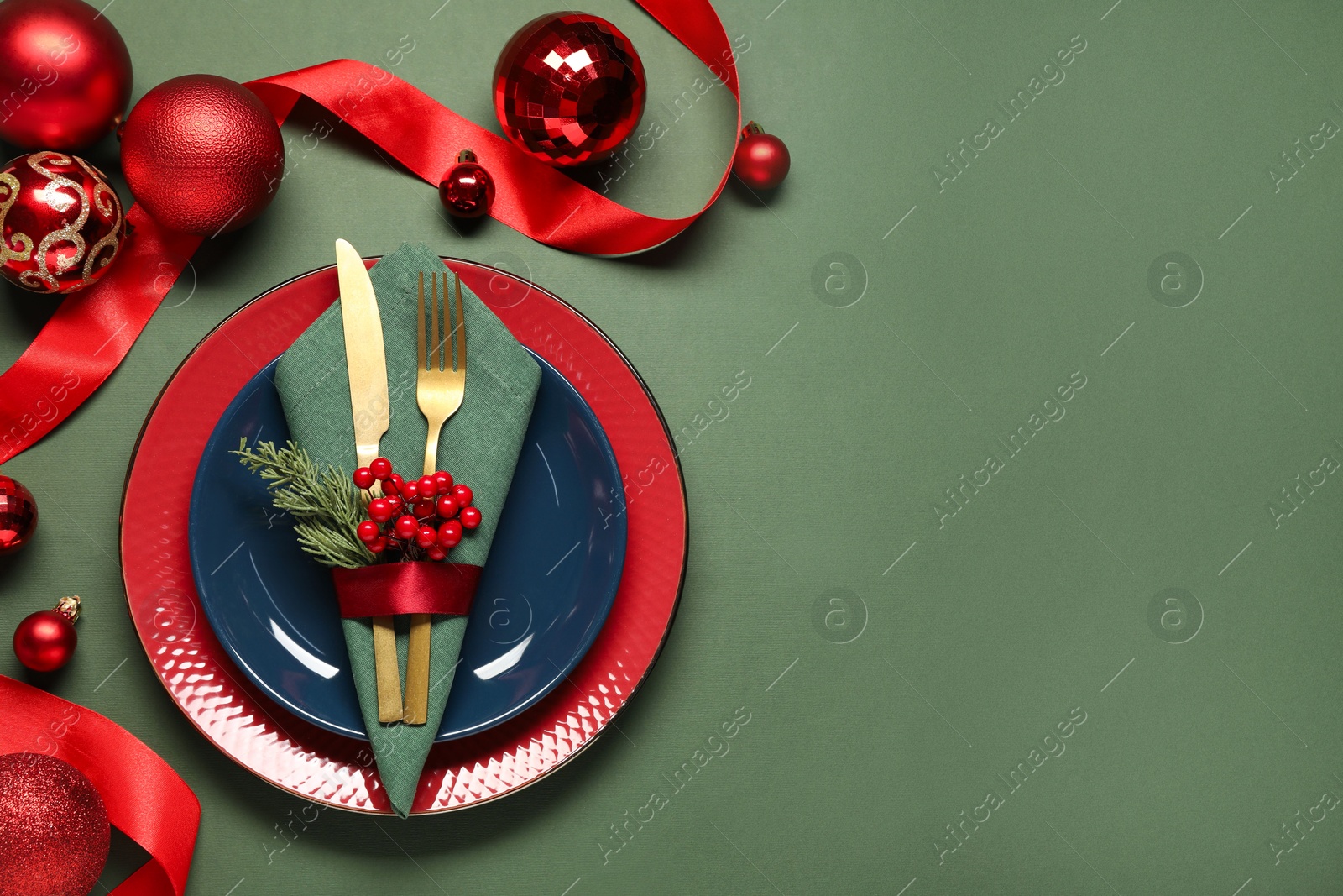 Photo of Christmas place setting with festive decor on green table, flat lay. Space for text