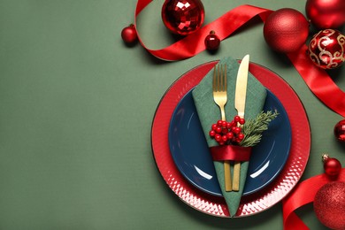 Photo of Christmas place setting with festive decor on green table, flat lay. Space for text