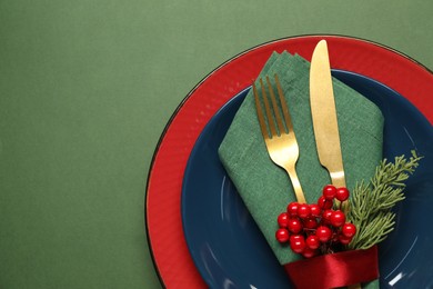 Photo of Christmas place setting and festive decor on green table, top view. Space for text