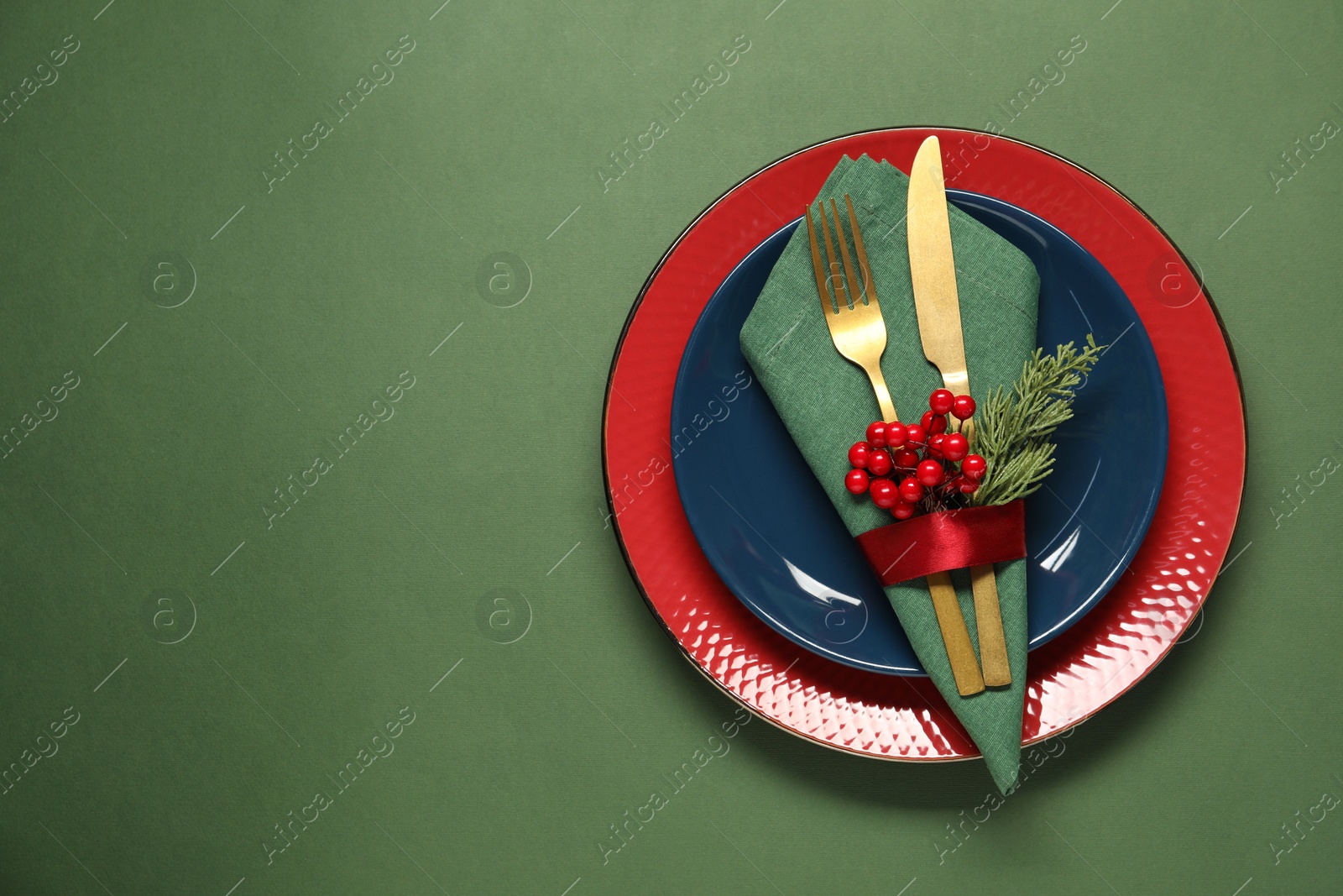 Photo of Christmas place setting and festive decor on green table, top view. Space for text