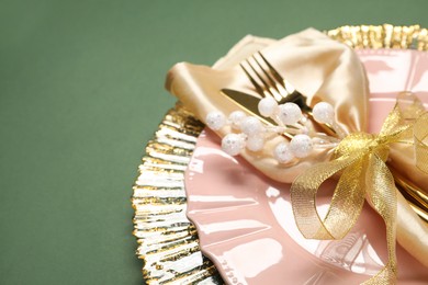 Photo of Christmas place setting and festive decor on green table, closeup. Space for text