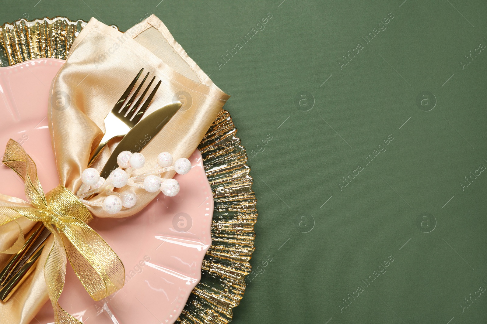 Photo of Christmas place setting and festive decor on green table, top view. Space for text