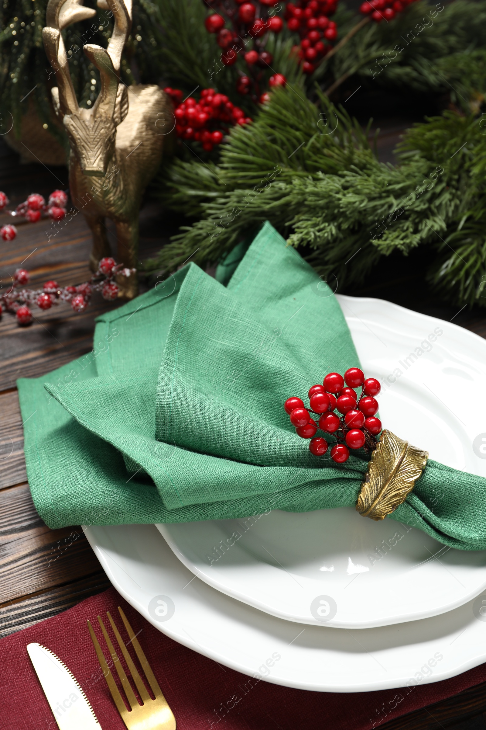 Photo of Christmas place setting with festive decor on wooden table, closeup