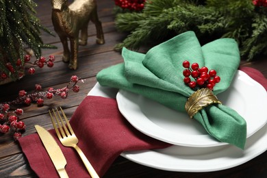 Photo of Christmas place setting with festive decor on wooden table, closeup