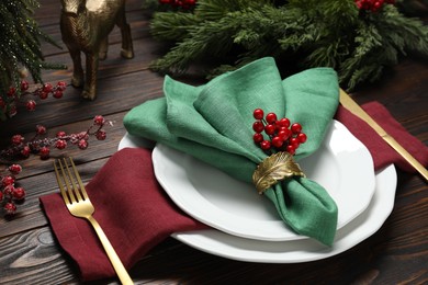 Photo of Christmas place setting with festive decor on wooden table, closeup