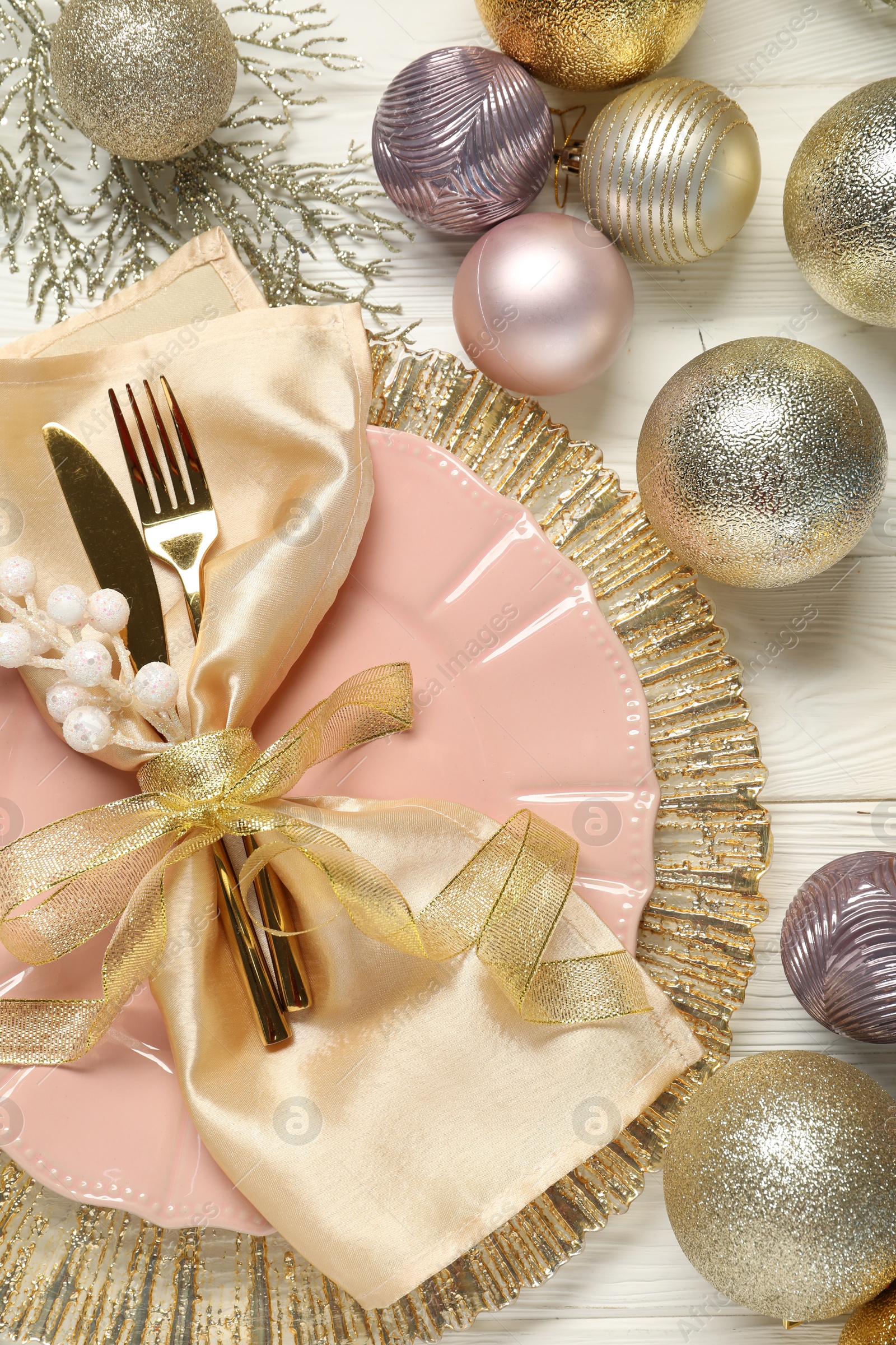 Photo of Christmas place setting with festive decor on white wooden table, flat lay