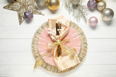 Photo of Christmas place setting with festive decor on white wooden table, flat lay