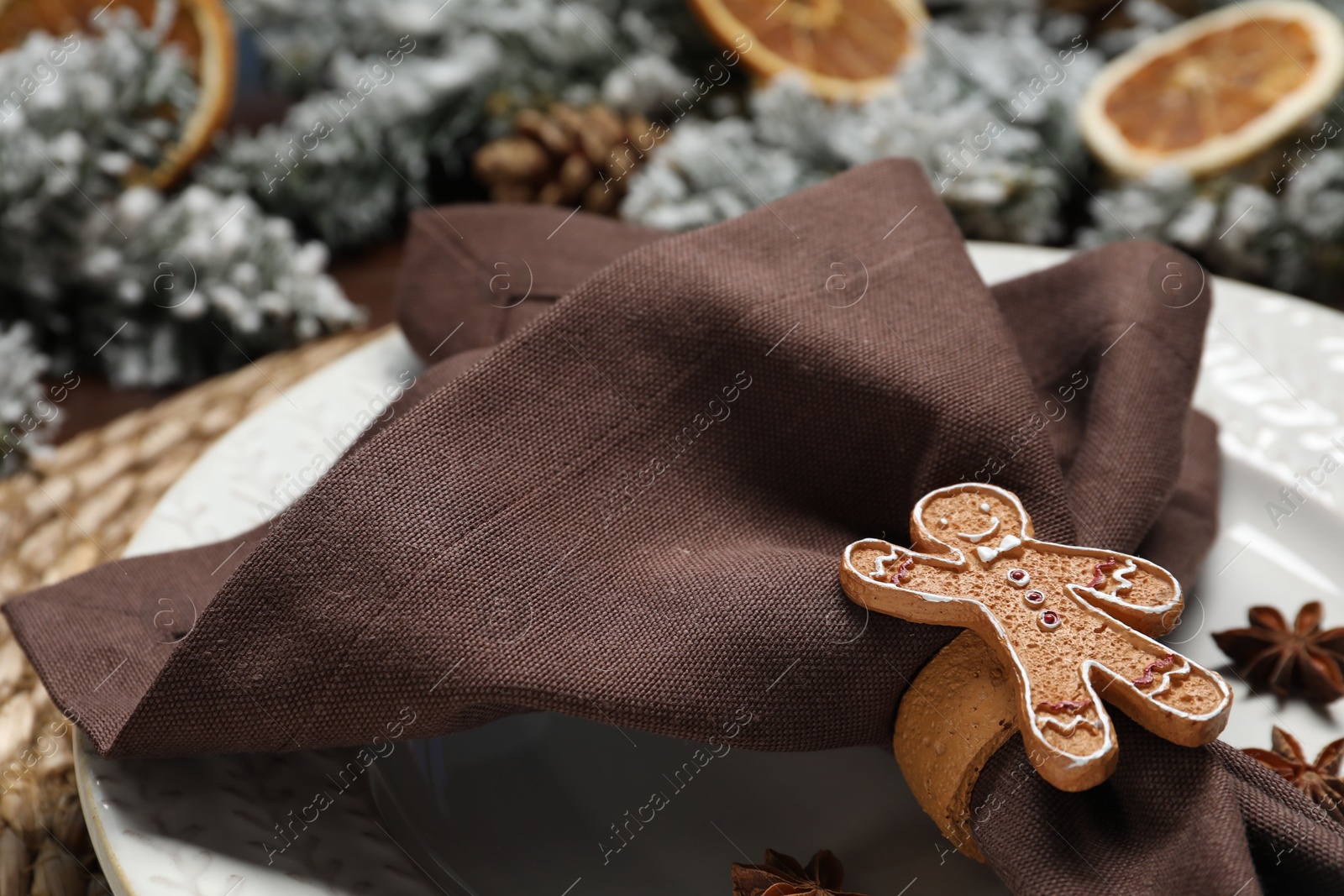 Photo of Christmas place setting with napkin, plate and festive decor on table, closeup