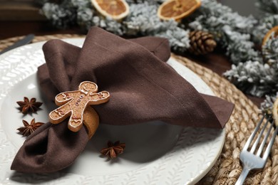 Photo of Christmas place setting with napkin, plate, cutlery and festive decor on table, closeup