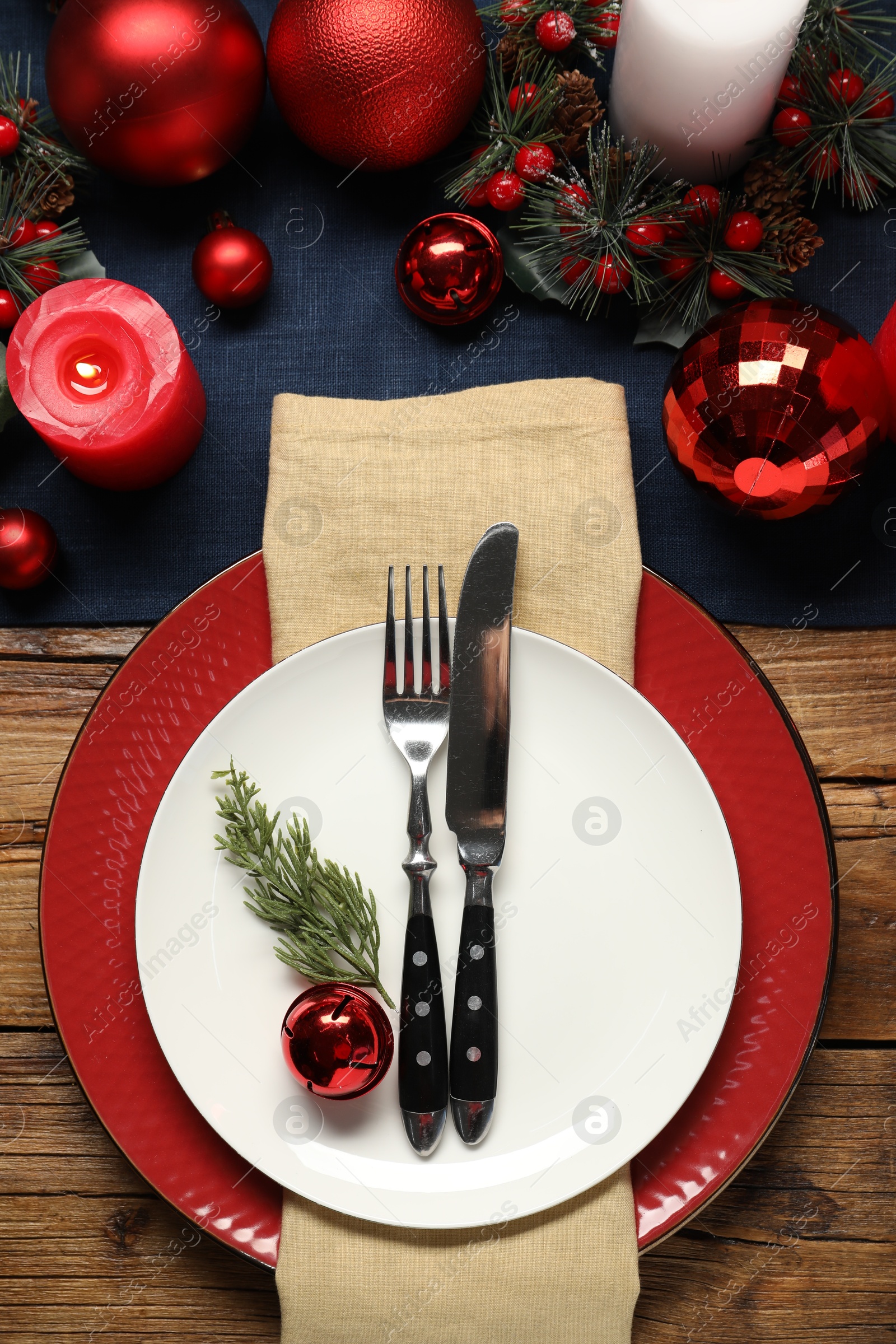 Photo of Christmas place setting with festive decor on wooden table, flat lay