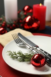 Photo of Christmas place setting with plates, cutlery and festive decor on table, closeup