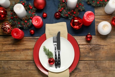 Photo of Christmas place setting with festive decor on wooden table, flat lay