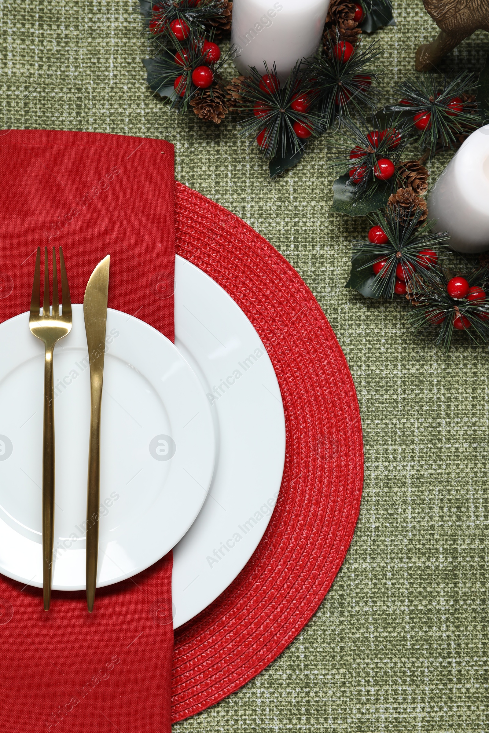 Photo of Christmas place setting with festive decor on green tablecloth, flat lay