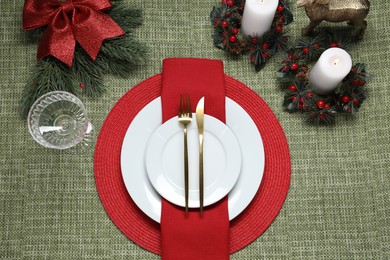 Photo of Christmas place setting with festive decor on green tablecloth, flat lay