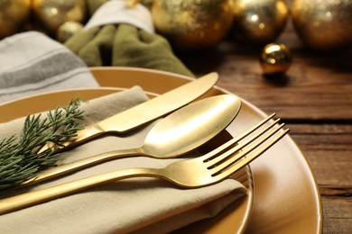 Photo of Christmas place setting with plates, cutlery and festive decor on wooden table, closeup