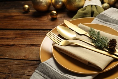 Photo of Christmas place setting with plates, cutlery and festive decor on wooden table, closeup. Space for text