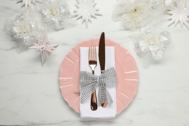 Photo of Christmas place setting with festive decor on white marble table, flat lay