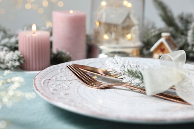 Photo of Christmas place setting with plate, cutlery and festive decor on table, closeup