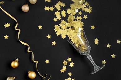 Photo of Flat lay composition with confetti and glass on black background. Christmas decor