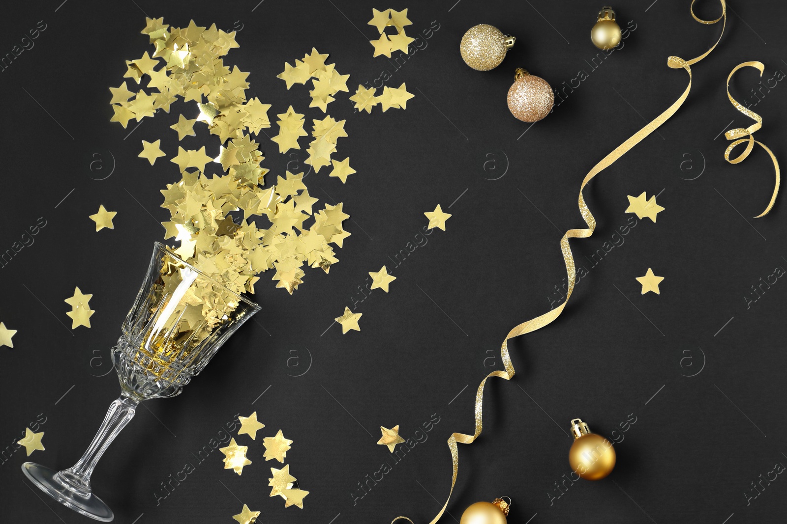 Photo of Flat lay composition with confetti and glass on black background. Christmas decor