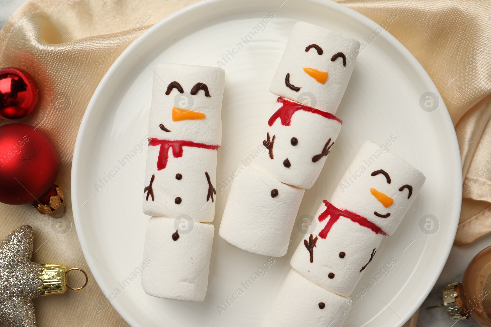 Photo of Funny marshmallow snowmen and festive decor on table, top view