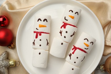 Photo of Funny marshmallow snowmen and festive decor on table, top view