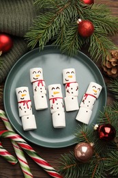 Photo of Funny marshmallow snowmen and festive decor on wooden table, flat lay