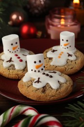 Photo of Funny marshmallow snowmen, cookies and festive decor on table, closeup