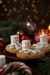 Photo of Funny marshmallow snowmen, cookies and festive decor on table