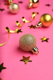 Photo of Confetti and Christmas balls on pink background, closeup