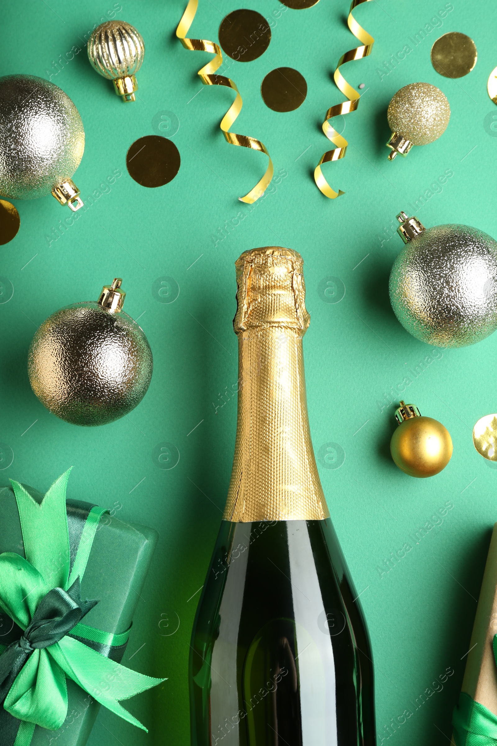 Photo of Flat lay composition with confetti and bottle of sparkling wine on green background. Christmas decor