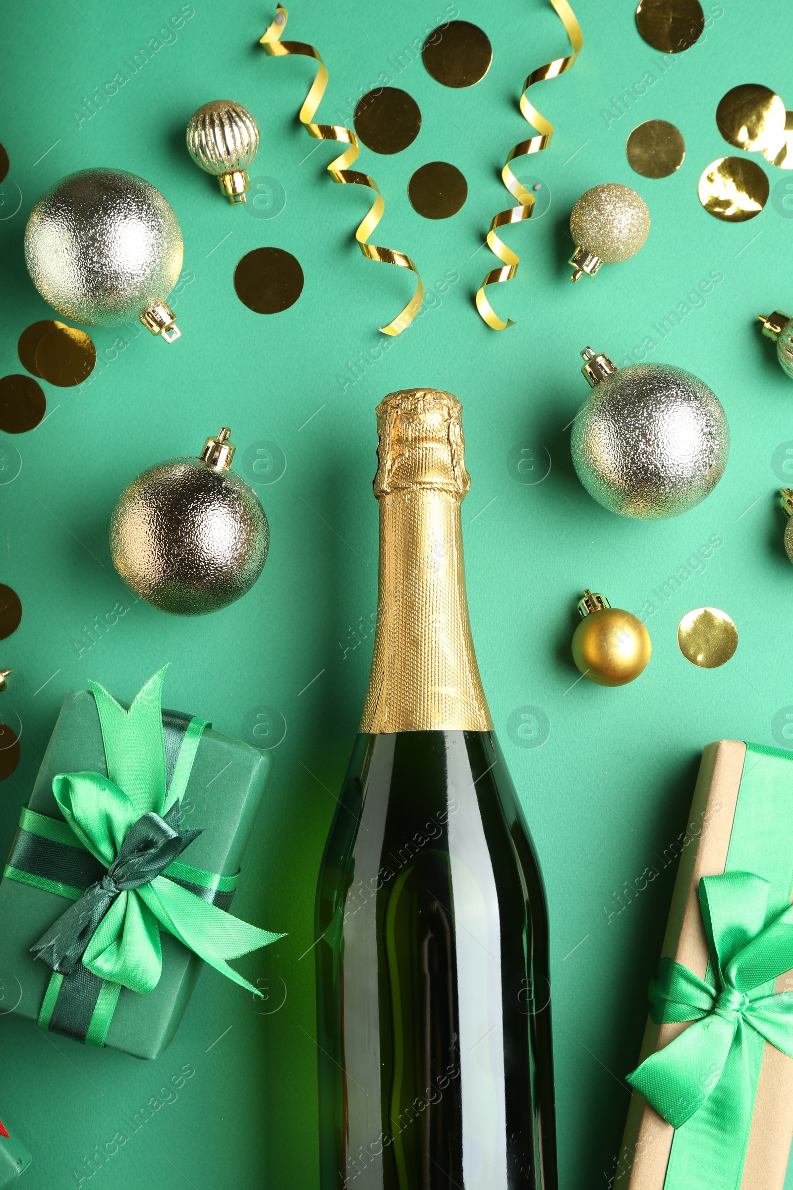 Photo of Flat lay composition with confetti and bottle of sparkling wine on green background. Christmas decor