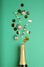 Photo of Bottle of sparkling wine and confetti on green background, flat lay. Christmas decor