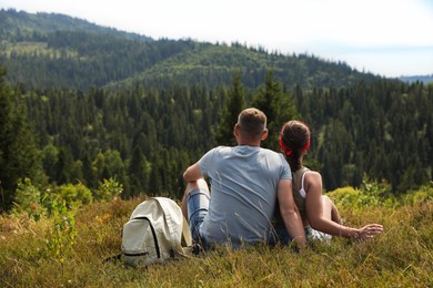 Photo of Couple with backpack enjoying picturesque landscape, back view. Active tourism