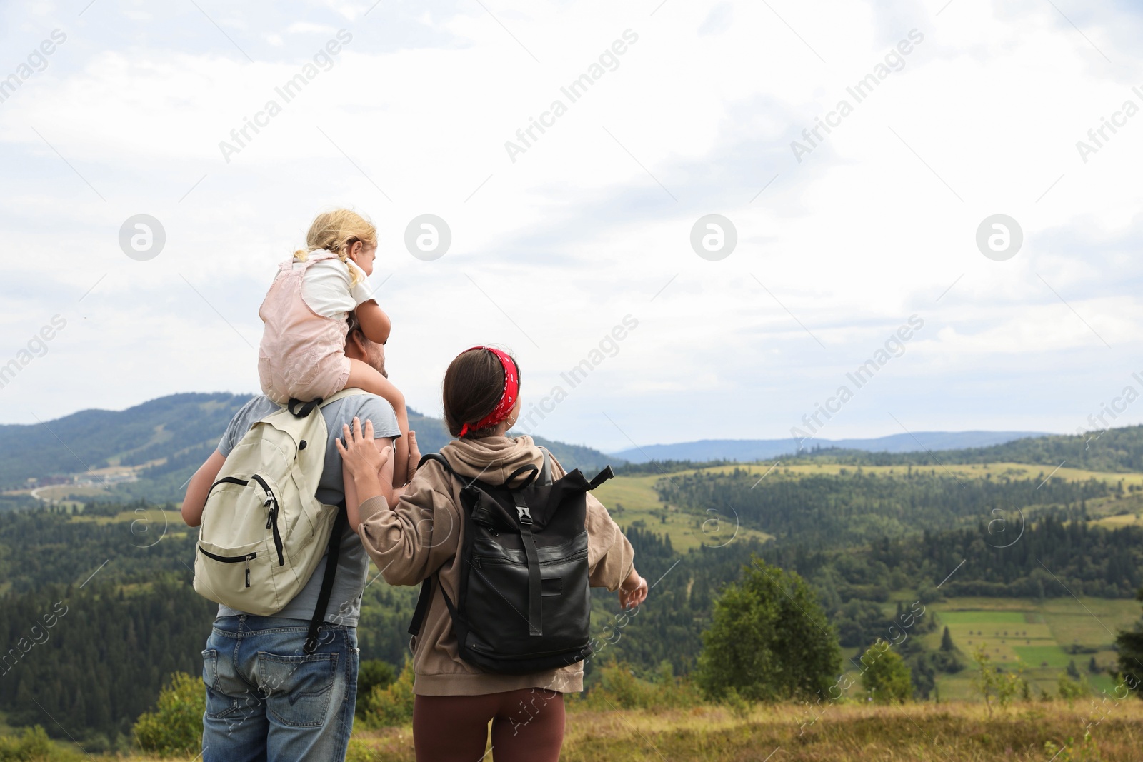 Photo of Family of tourists with backpacks enjoying picturesque landscape, back view. Space for text