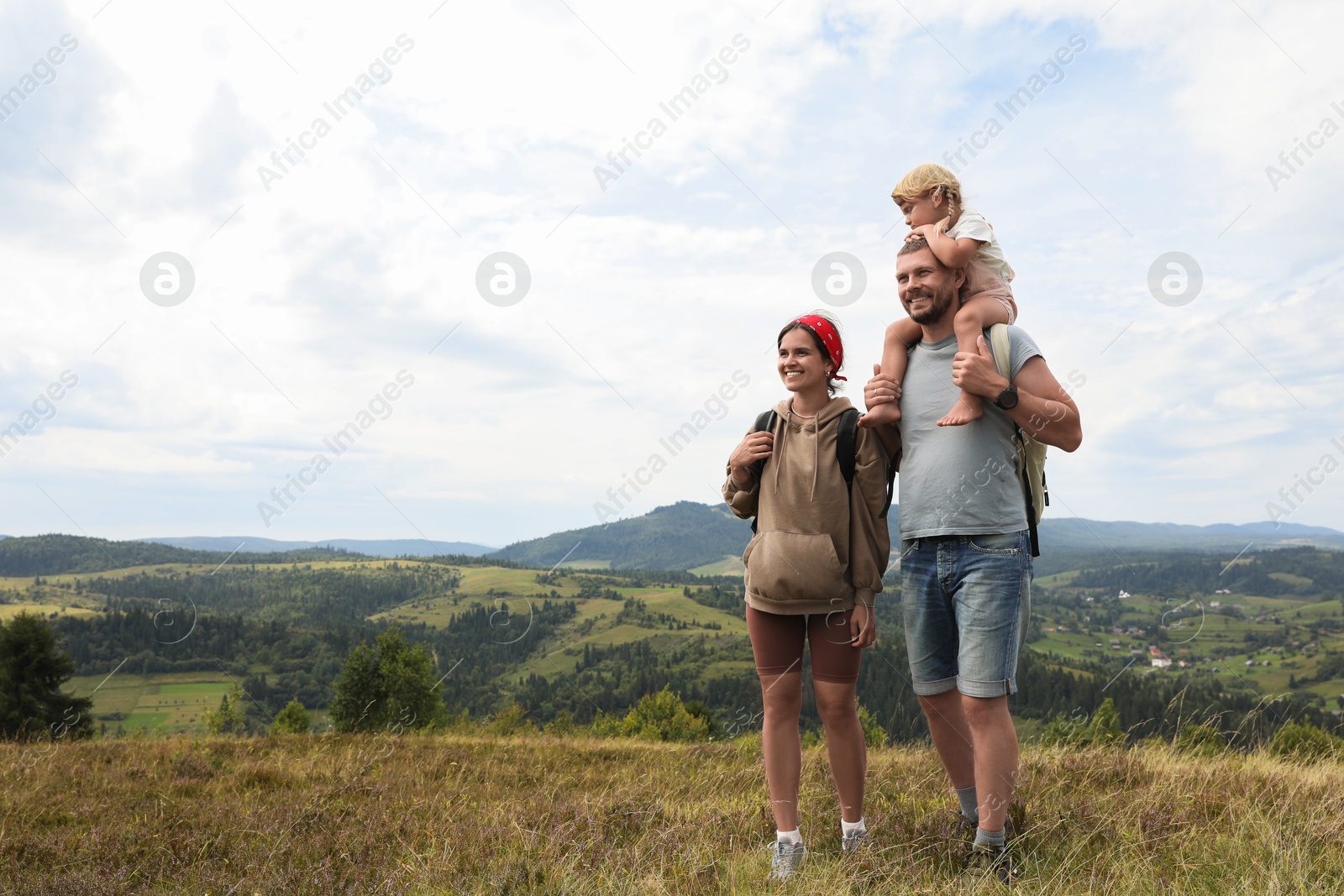 Photo of Happy family with backpacks travelling in mountains, space for text. Active tourism