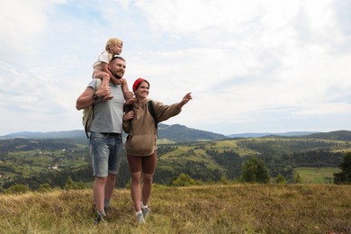 Photo of Happy family with backpacks travelling in mountains, space for text. Active tourism