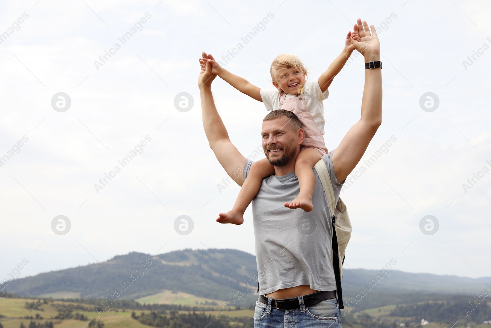 Photo of Happy tourist with his daughter and backpack travelling in mountains. Space for text