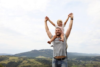 Photo of Happy tourist with his daughter and backpack travelling in mountains. Space for text