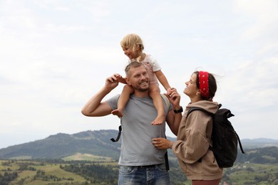 Photo of Happy family with backpacks travelling in mountains, space for text. Active tourism