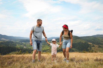 Photo of Happy family with backpacks travelling in mountains. Active tourism