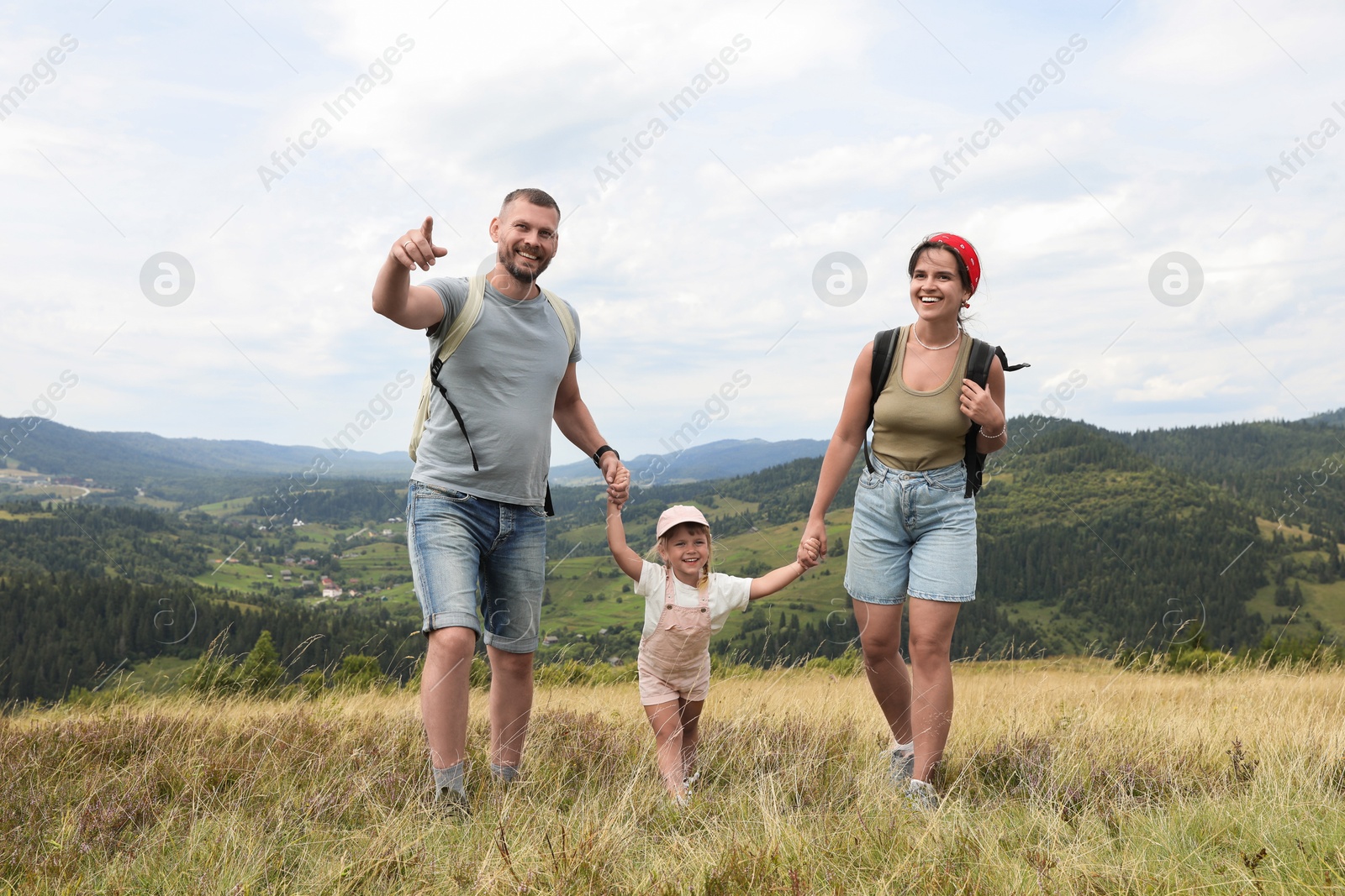 Photo of Happy family with backpacks travelling in mountains. Active tourism